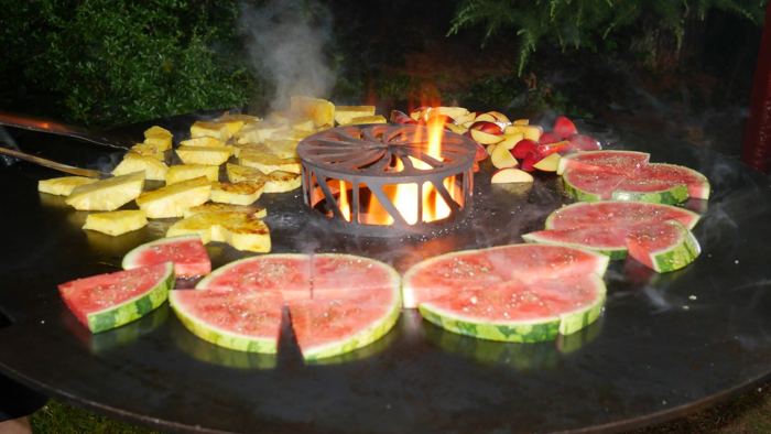 Griller an der BBQ-Theke unter orangefarbenem Pavillon mit Menütafel bei einem Firmen-BBQ