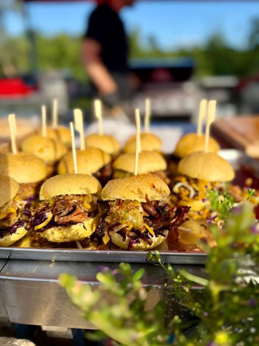 Zwei Griller am Smoker unter Zelt bei einem Firmen-BBQ – Zubereitung am Grillfahrzeug