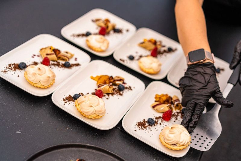 Angerichtete Dessertteller mit Tartelettes, Beeren und Crêpes werden serviert