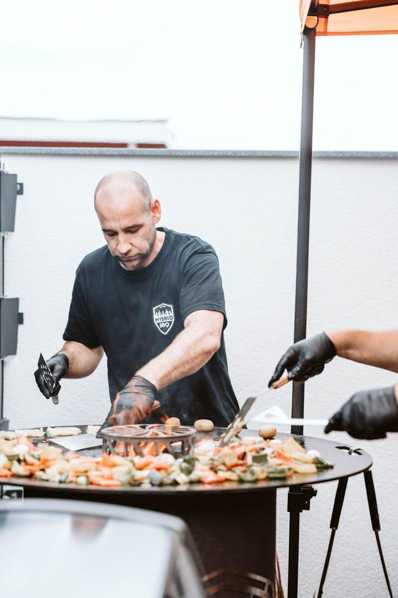 Michael Kisperth wendet Gemüse und Kartoffeln auf der Plancha-Feuerplatte