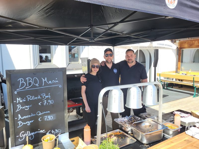 Grillstation unter dem Zelt mit BBQ-Menütafel bei einer Feier im Freien