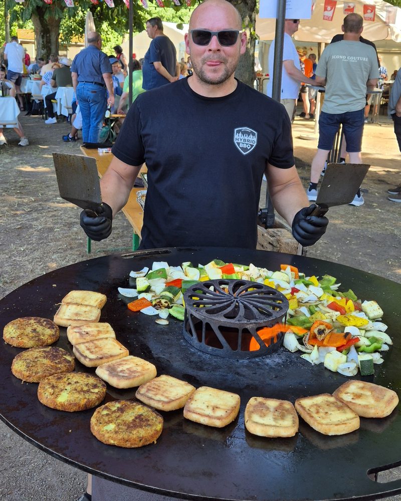Mitarbeiter von Hybrid BBQ an der Feuerplatte mit gegrilltem Gemüse und Halloumi